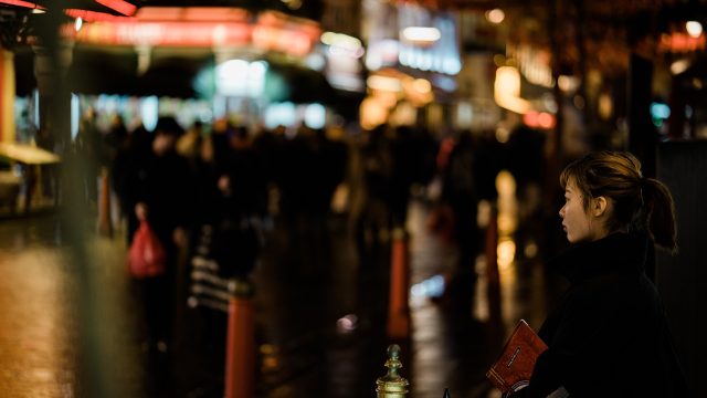 四虎视频域名 都市悬疑剧海报风格的画面，雨夜街头霓虹倒映在湿漉漉的路面上，主角背影站在巷口